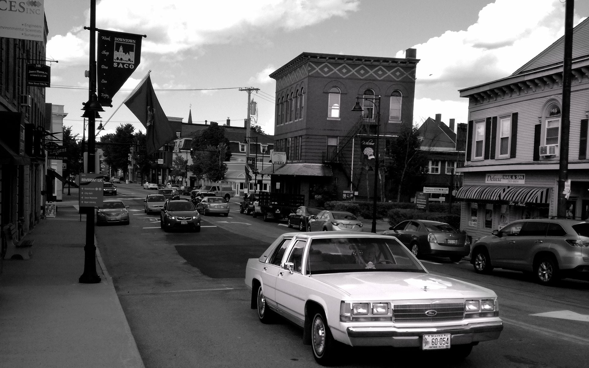 Cars parked along a coastal Maine town street near a working harbor on a summer afternoon